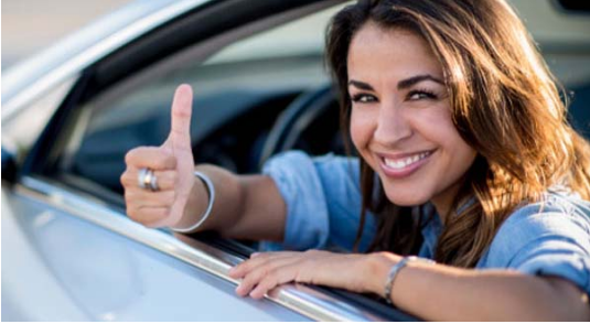 Conductora sonriente con el pulgar arriba desde su coche